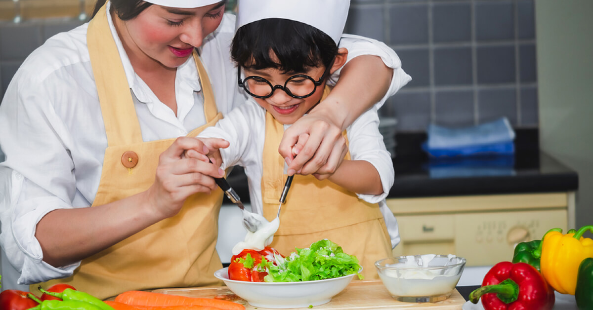 Seorang ibu mengajarkan cara memasak kepada anaknya sebagai kegiatan untuk mengoptimalkan perkembangan anak